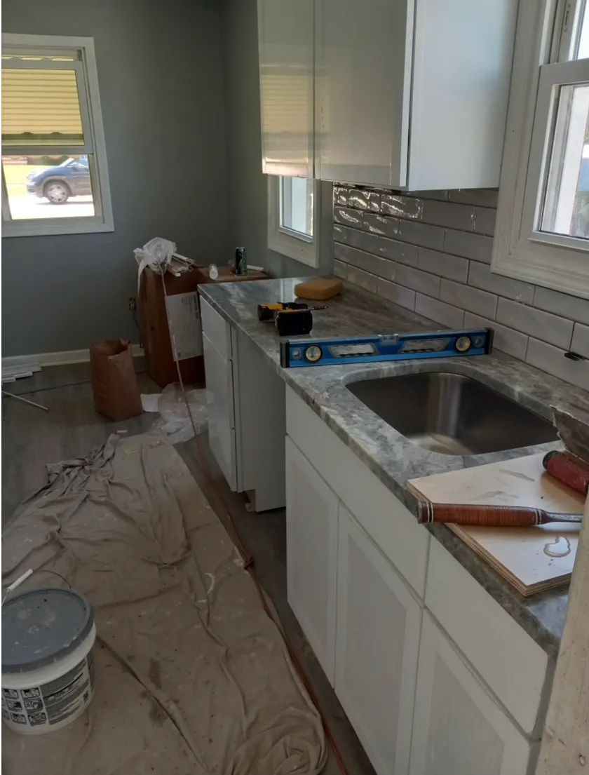 A kitchen part-way through installation, with counters going in, a level on the worktop and dust sheets down