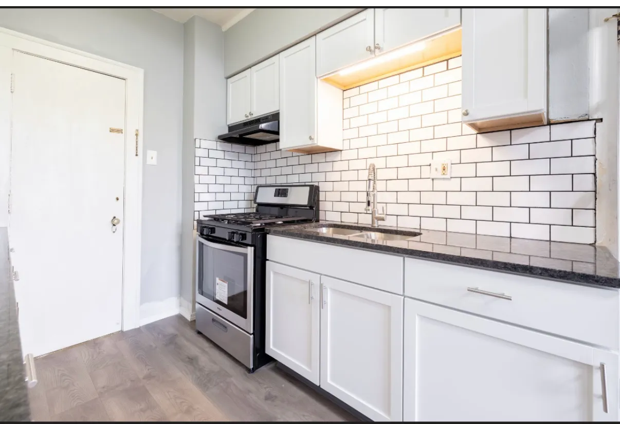 Kitchen with white shaker cabinets, subway tile, dark counters and a stainless range